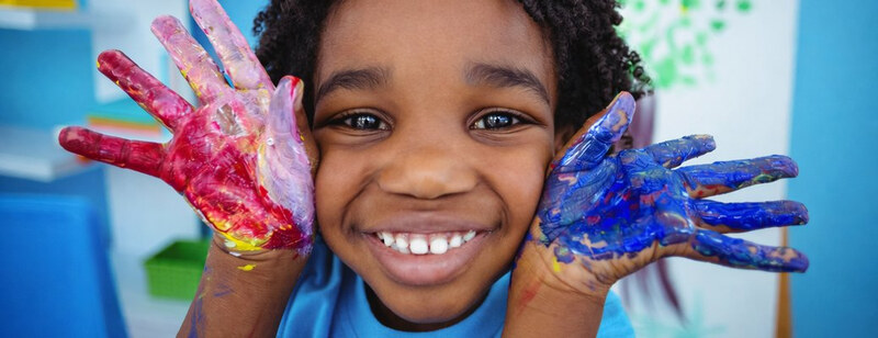 Fruity Club: a smiling child holding up hands covered in red and blue paint
