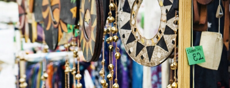 Fair trade crafts: painted wall hangings, a mosaic mirror and brass bells
