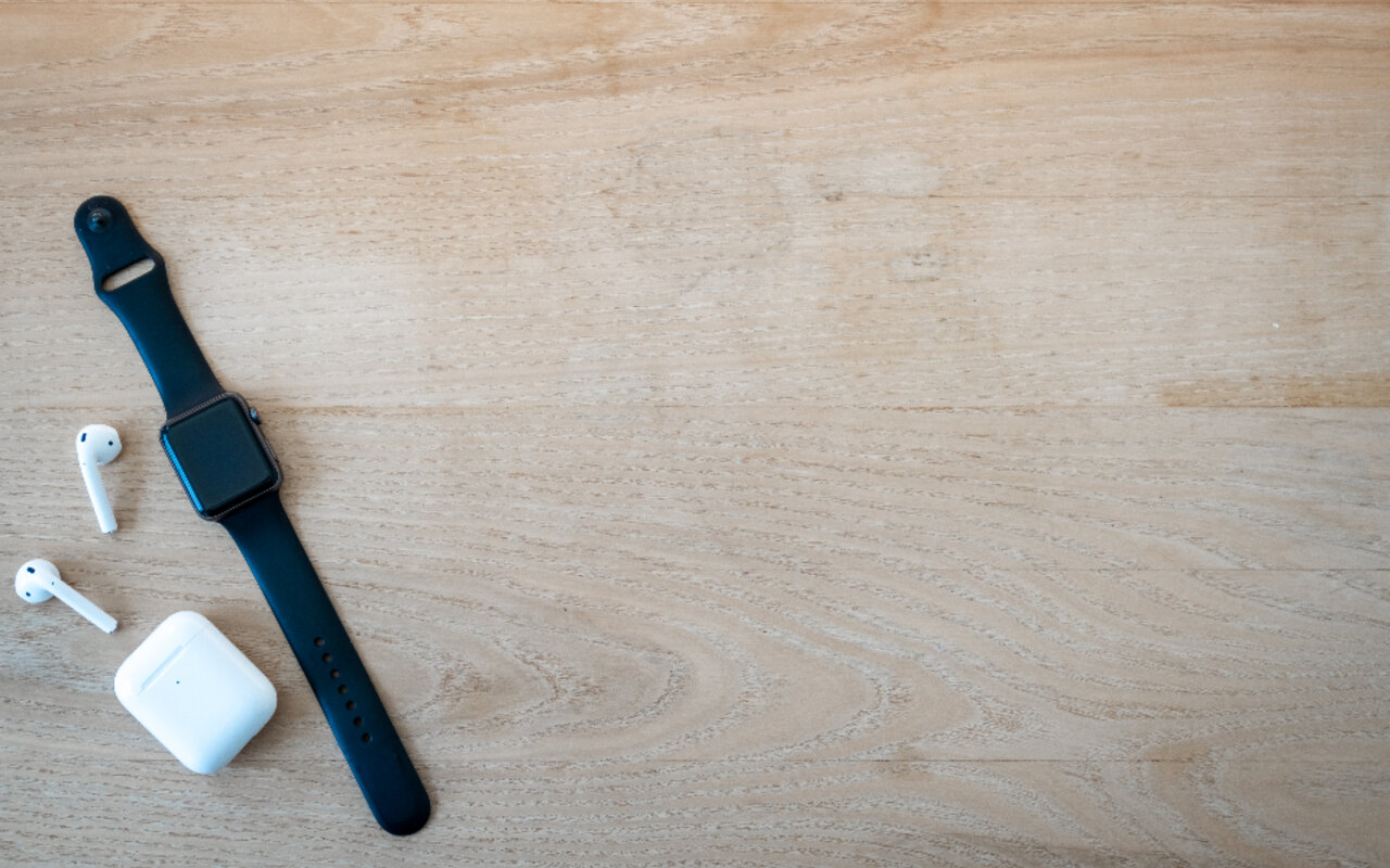 Une Apple Watch et des écouteurs sans fil sur une surface en bois